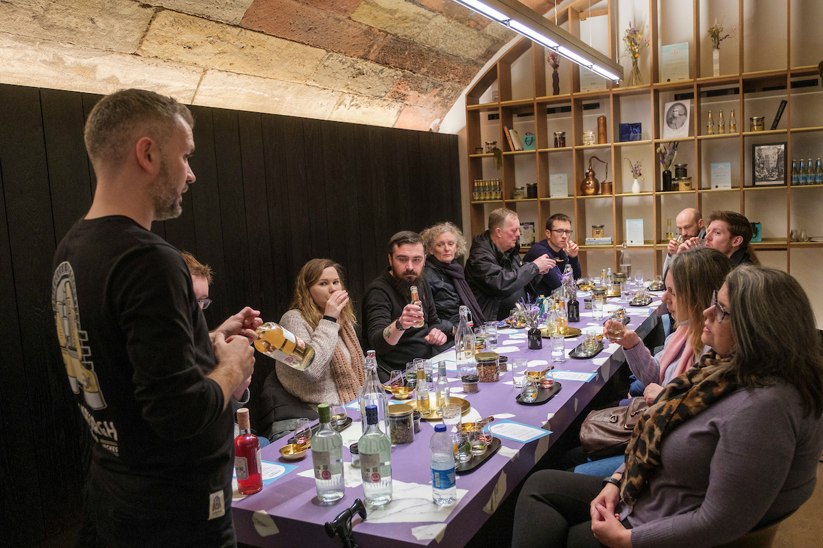 Guide leads a whisky tasting group seated at a long purple-clothed table