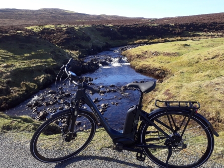 An e-bike beside a rocky burn.