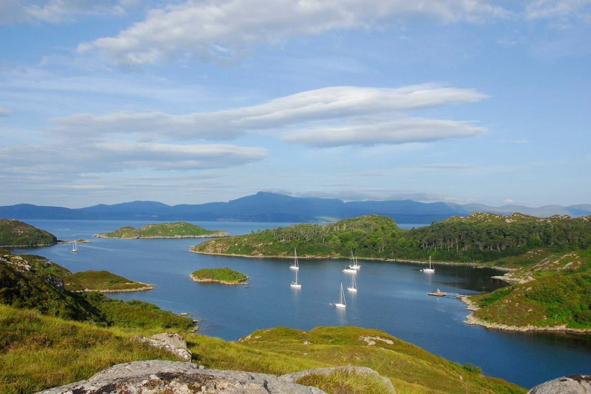 Yachts at anchor among the low green islands and inlets off Rona.