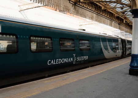 Caledonian Sleeper carriage waiting at a station platform under a glass roof