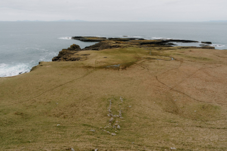 Grassy headland with a stony path leading towards rocky sea cliffs