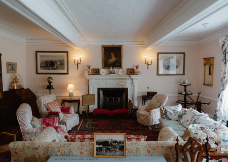 Sitting room with white fireplace, portrait and framed prints, sofas draped in floral covers