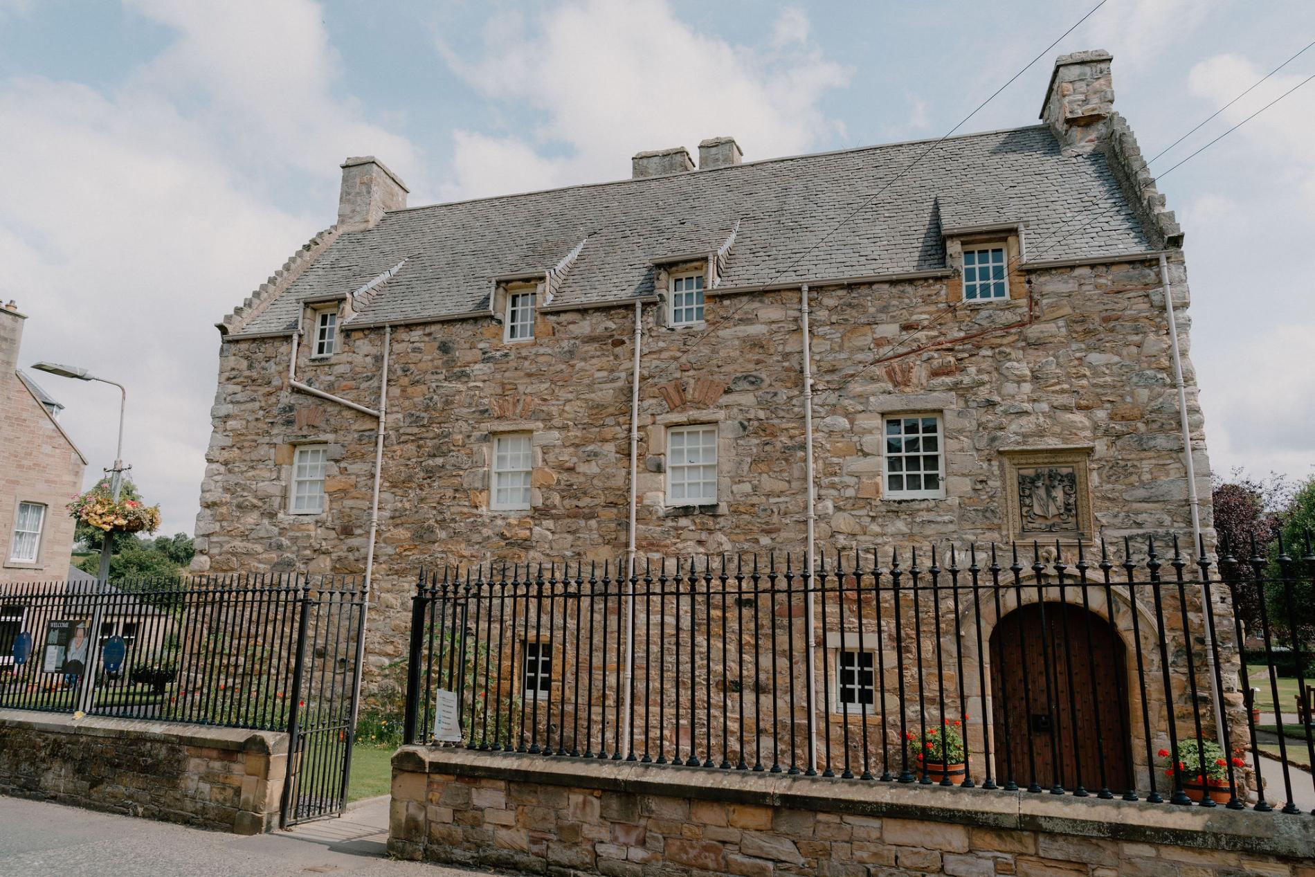 Stone tower house with dormer windows behind black iron railings