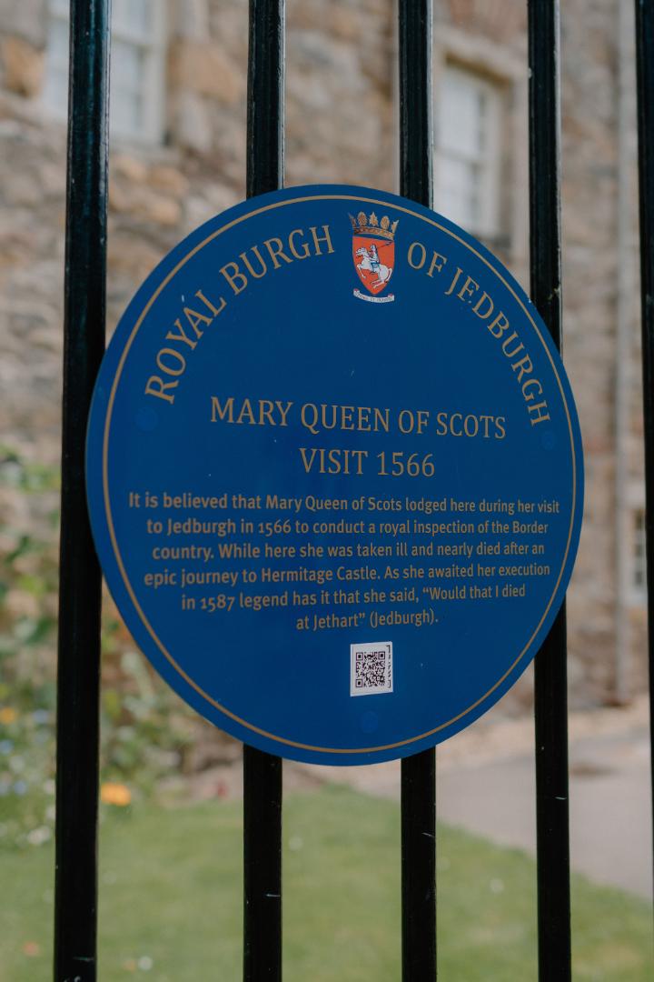 Blue plaque behind railings marking Mary Queen of Scots' visit to Jedburgh in 1566