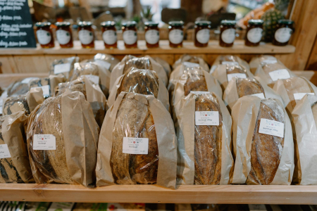 Wrapped sourdough loaves on a shelf below rows of jam jars