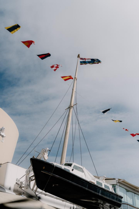 Signal flags strung from the mast of a moored boat against grey sky