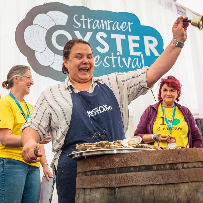 Woman rings a bell shucking oysters at Stranraer Oyster Festival
