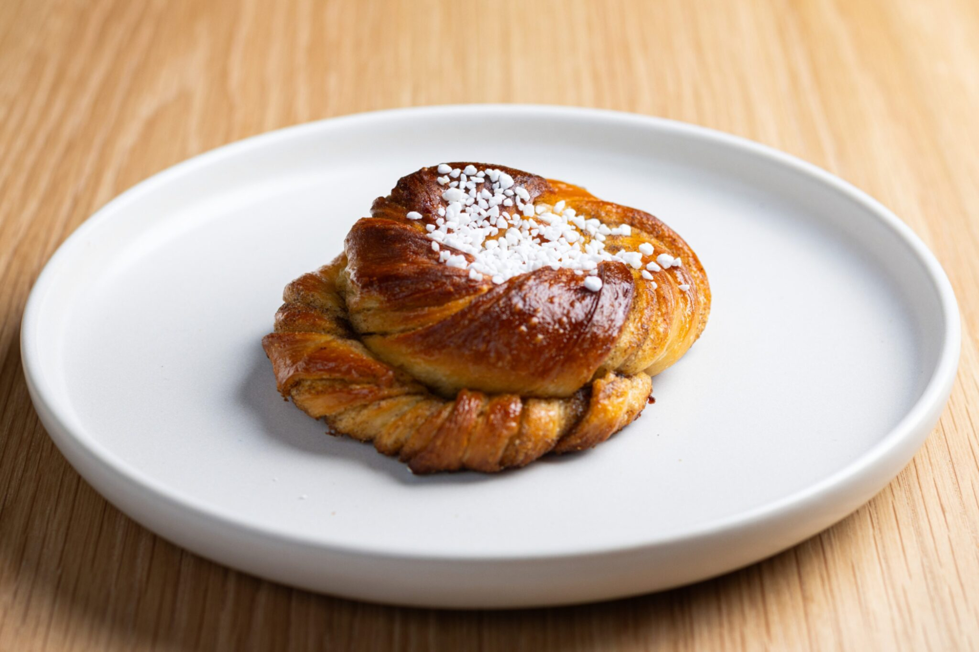 A sugared cinnamon bun on a white plate at Grounded.