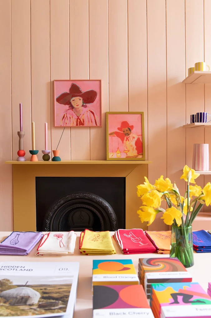 A painted fireplace with prints, candles and daffodils.