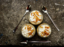 Three glasses of dessert topped with orange peel on a stone table, No88.