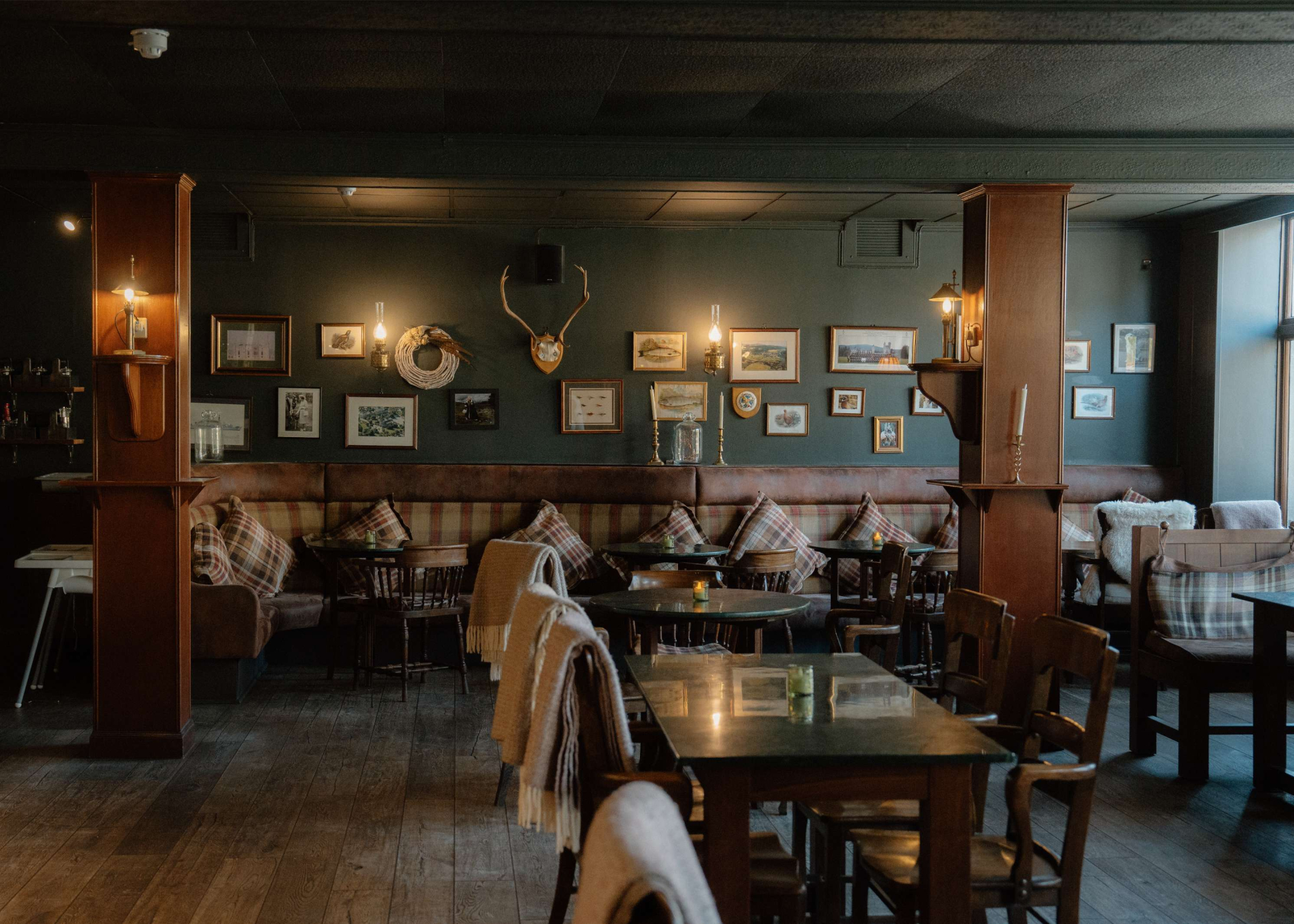 The Balmoral Arms' dining room, dark walls hung with pictures above tartan banquettes.