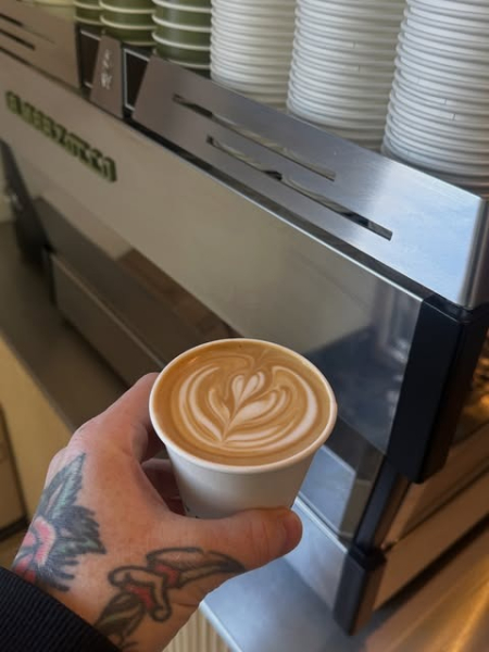 A flat white with latte art held by the coffee machine.